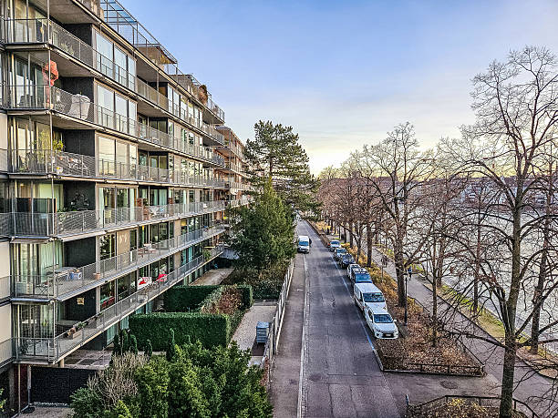 Contemporary residential apartment building with balconies along a quiet riverside street. Urban living, modern architecture, calm evening city atmosphere. High quality photo