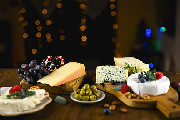 Arranging various cheeses, fresh fruit, and olives on a wooden board