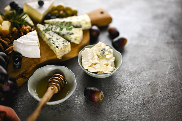 Cheese board offering an assortment of cheeses, grapes, nuts, rosemary, honey, and creamy blue cheese