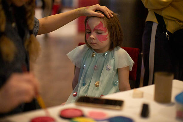 istock Young girl with butterfly face paint at craft table before appearance 2252370714