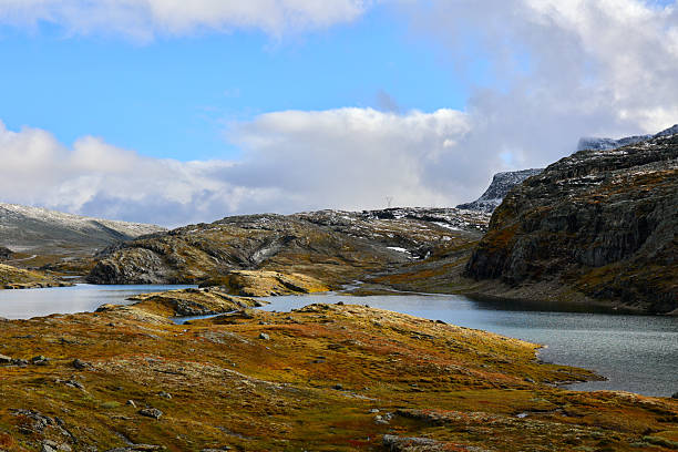 Tranquil lakes cut through rocky tundra beneath cloud-filled skies along the Bjørgavegen road on the National Tourist Route Aurlandsfjellet. This image showcases the expansive and isolated mountain landscapes of Aurland, Vestland county, Norway.