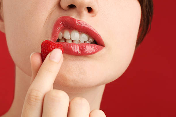 istock Woman with beautiful lips makeup and raspberry on red background, closeup 2252376383