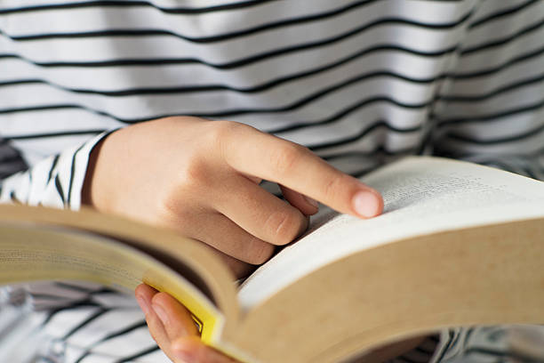 istock Person Holding Thick Book in Striped Shirt 2252377120