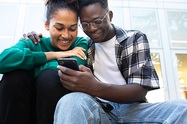 istock Young diverse couple sharing smartphone screen outdoors 2252379824