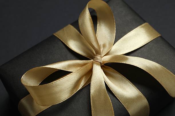 istock Beautiful gift box with a golden bow on black background 2252381774