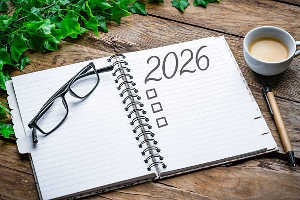 istock Overhead view of a notepad with 2026 New Year resolution or personal goals. Coffee cup, eyeglasses and pen. Target, plan, action, checklist for the coming year. 2252382416