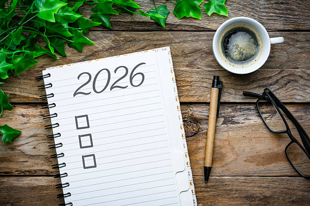 istock Overhead view of a notepad with 2026 New Year resolution or personal goals. Coffee cup, eyeglasses and pen. Target, plan, action, checklist for the coming year. 2252382422