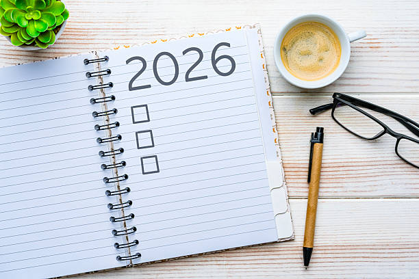 istock Overhead view of a notepad with 2026 New Year resolution or personal goals. Coffee cup, eyeglasses and pen. Target, plan, action, checklist for the coming year. 2252382429