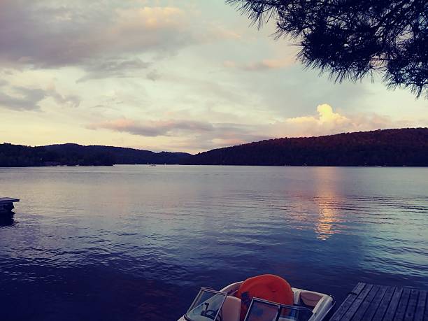Sunset View on Canada Lake in the Adirondack Mountains on a summer night with a speed boat moored at the dock.