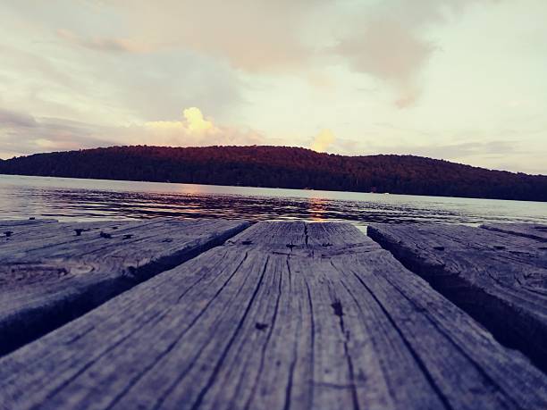 View from on old wooden dock on a lake in the mountains during a summer sunset.