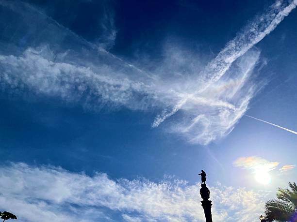 Barcelona, Cataluña, Spain - October 24, 2025: Statue of Christopher Columbus standing atop the Columbus Monument, reaching towards the sea under a vibrant blue sky with wispy clouds, symbolizing exploration, travel, and historical landmarks