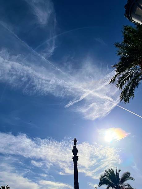 Barcelona, Cataluña, Spain - October 24, 2025: Statue of Christopher Columbus standing atop the Columbus Monument, reaching towards the sea under a vibrant blue sky with wispy clouds, symbolizing exploration, travel, and historical landmarks