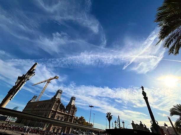 Barcelona, Cataluña, Spain - October 24, 2025: Statue of Christopher Columbus standing atop the Columbus Monument, reaching towards the sea under a vibrant blue sky with wispy clouds, symbolizing exploration, travel, and historical landmarks