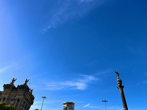 Barcelona, Cataluña, Spain - October 24, 2025: Statue of Christopher Columbus standing atop the Columbus Monument, reaching towards the sea under a vibrant blue sky with wispy clouds, symbolizing exploration, travel, and historical landmarks