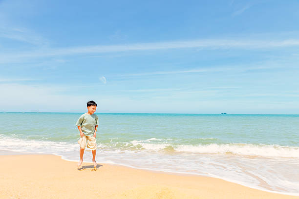 One little Asian kid playing with water on beach Dajiao Park in Qizi Bay (Qiziwan), Changjiang, Hainan, China