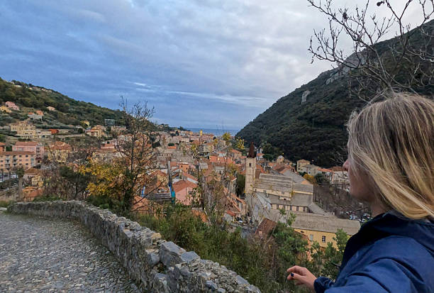 istock Young woman walks along cobblestone pathway above village 2252387238
