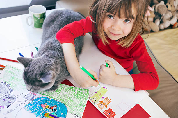 istock Happy boy drawing at home while cat rests on drawings 2252387464