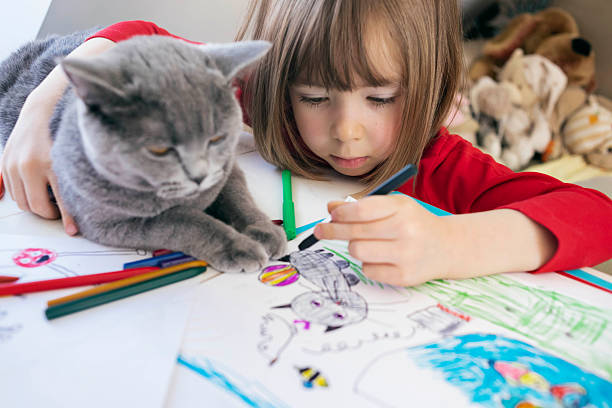 istock Focused child making colorful art drawings as cat sits on table 2252387493