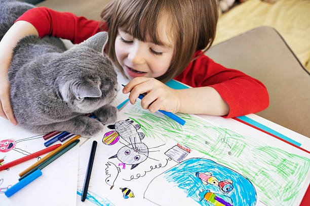 istock A child hugs a cat at a drawing table surrounded by cheerful children's drawings 2252387498