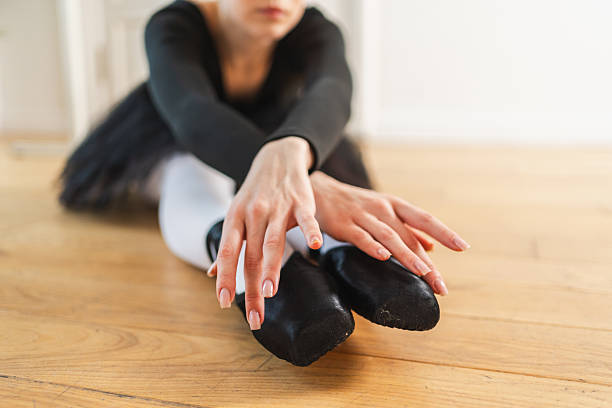 Low section of female dancer wearing ballet shoes standing on tiptoes at studio