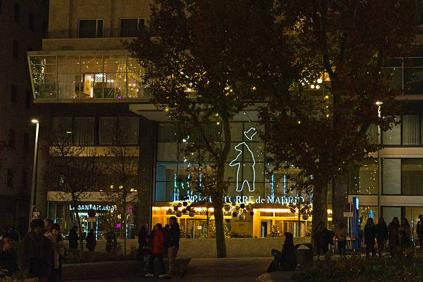 Spain, Madrid, Christmas, 12-12-2025: People walking and standing on the street in front of a modern building at night