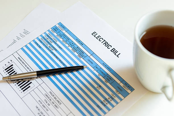 Electricity bill document with pen and coffee cup on desk representing household energy costs, monthly expenses, budgeting and utility payment concept.