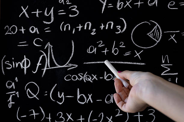 Mathematics and education concept showing hand writing algebra and trigonometry formulas on a blackboard with chalk, representing learning, teaching, problem solving and academic study.