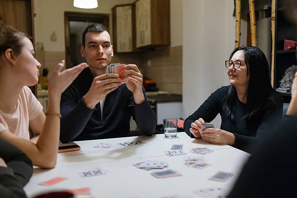Group of people sitting at dining table and playing cards during a casual home gathering