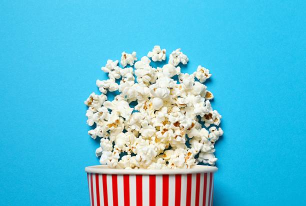 istock Delicious popcorn in a striped cardboard basket on a colored background 2252412736