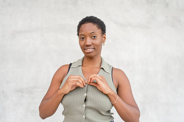 istock Young woman buttoning her top against gray wall 2252414611