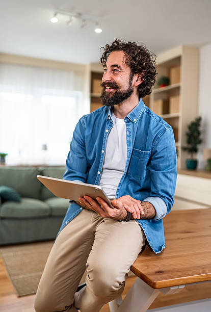 istock Smiling man holding digital tablet at home 2252416424