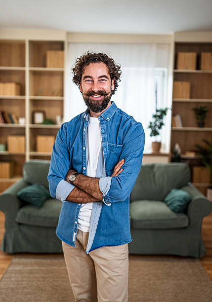 istock Smiling man standing with arms crossed at home 2252416442