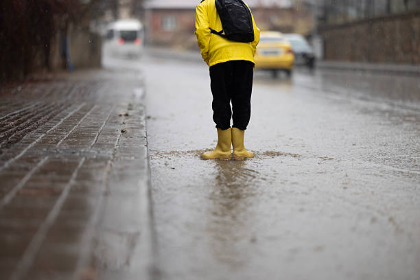 POV shot of person with Rain Boots standing in Floodwater. Flooding, climate change, and environmental impact by heavy rain