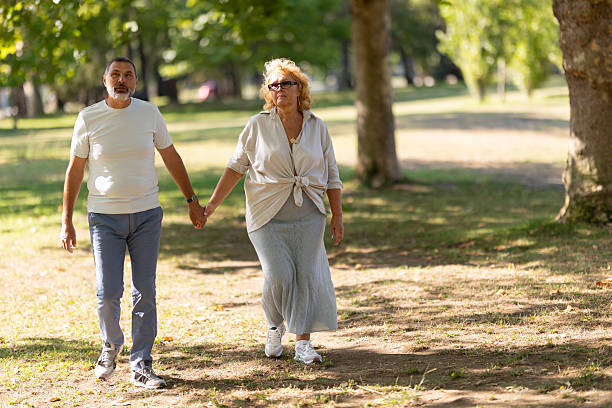 istock Senior couple holding hands walking in summer park 2252420961
