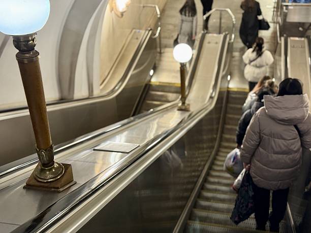 istock Urban Transit Scene, Commuters On Escalator During Winter, Passengers Move Along Handrails In Subway Station, City Travelers In Winter Coat Using Escalator With Vintage Lighting 2252420983