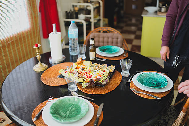 Dining table set for a casual meal with fresh mixed greens salad topped with pomegranate seeds and crispy fried fish, ready to serve guests in a cozy home kitchen