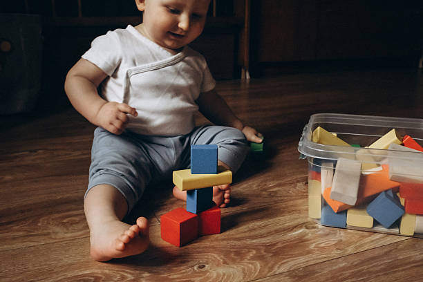 istock Baby Stacking Colorful Blocks on Wooden Floor 2252425203