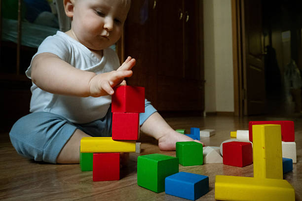 istock Baby Stacking Colorful Blocks on Wooden Floor 2252425374