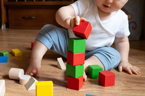 istock Baby Stacking Colorful Blocks on Wooden Floor 2252425418