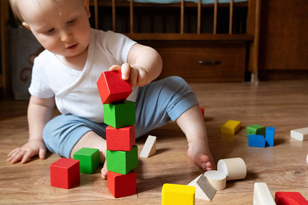 istock Baby Stacking Colorful Blocks on Wooden Floor 2252425419