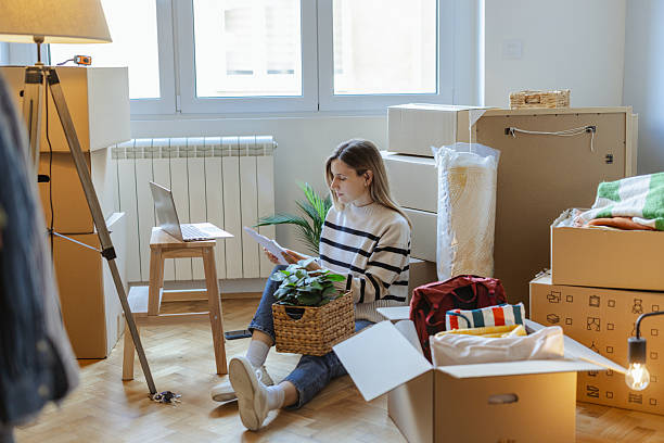 istock Woman reviewing documents while preparing for a home relocation surrounded by moving boxes 2252429546