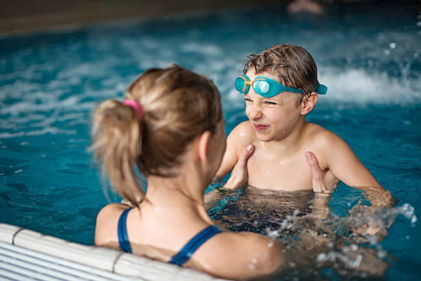 istock Mother teaching son to swim while playing at indoor pool 2252435547