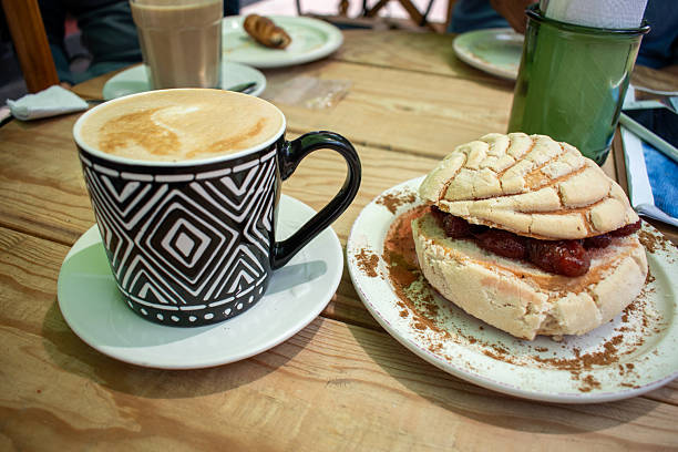 Traditional Mexican concha bread with jam and coffee on rustic wooden table