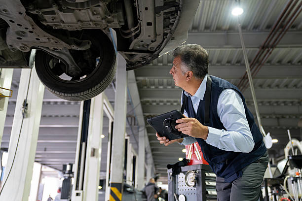 istock Mechanic looking under a car at a garage while holding a tablet 2252437452