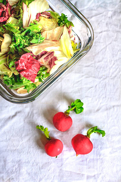 Top view of a fresh and colorful vegetable salad made with radishes, lettuce, and tomatoes, served in bowls on a light table. The image represents healthy eating, clean food, plant-based nutrition, fresh ingredients, and balanced lifestyle. Perfect for concepts such as vegan and vegetarian diet, organic food, meal preparation, detox, and healthy living.