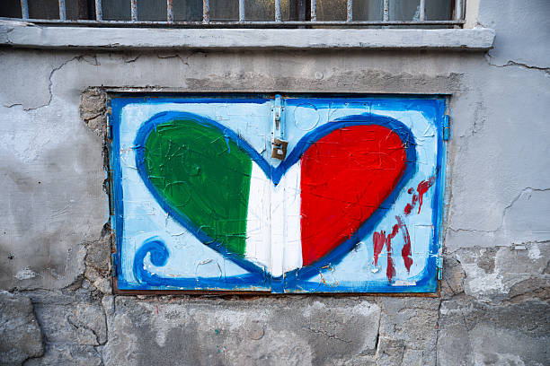 Black heart graffiti is painted on a cracked beige wall. grunge texture, creative urban art background. Concept of love, heart, imperfection within street art