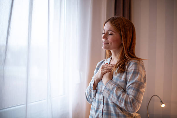 istock Woman standing by window practicing gratitude and mindfulness 2252445254