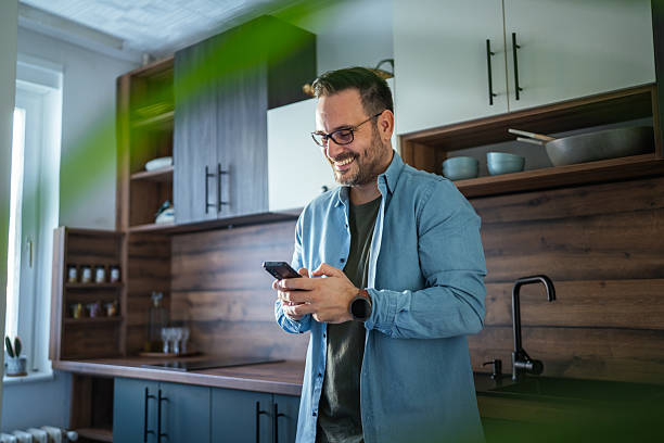 istock Happy man communicating on smart phone in modern kitchen 2252447177
