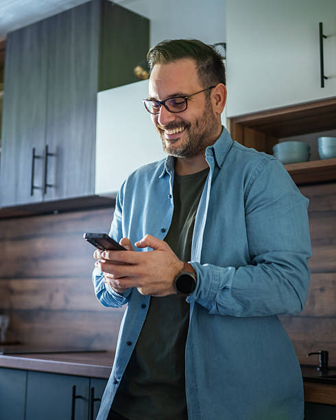 istock Happy man communicating on smart phone in modern kitchen 2252447256
