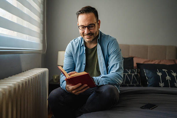 istock Man reading book relaxing in bedroom 2252448309